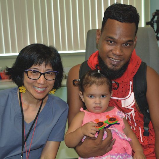 A man and woman are holding a little girl in their arms.