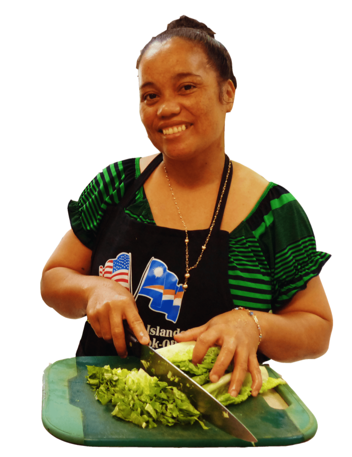 A woman in an apron is cutting lettuce on a cutting board