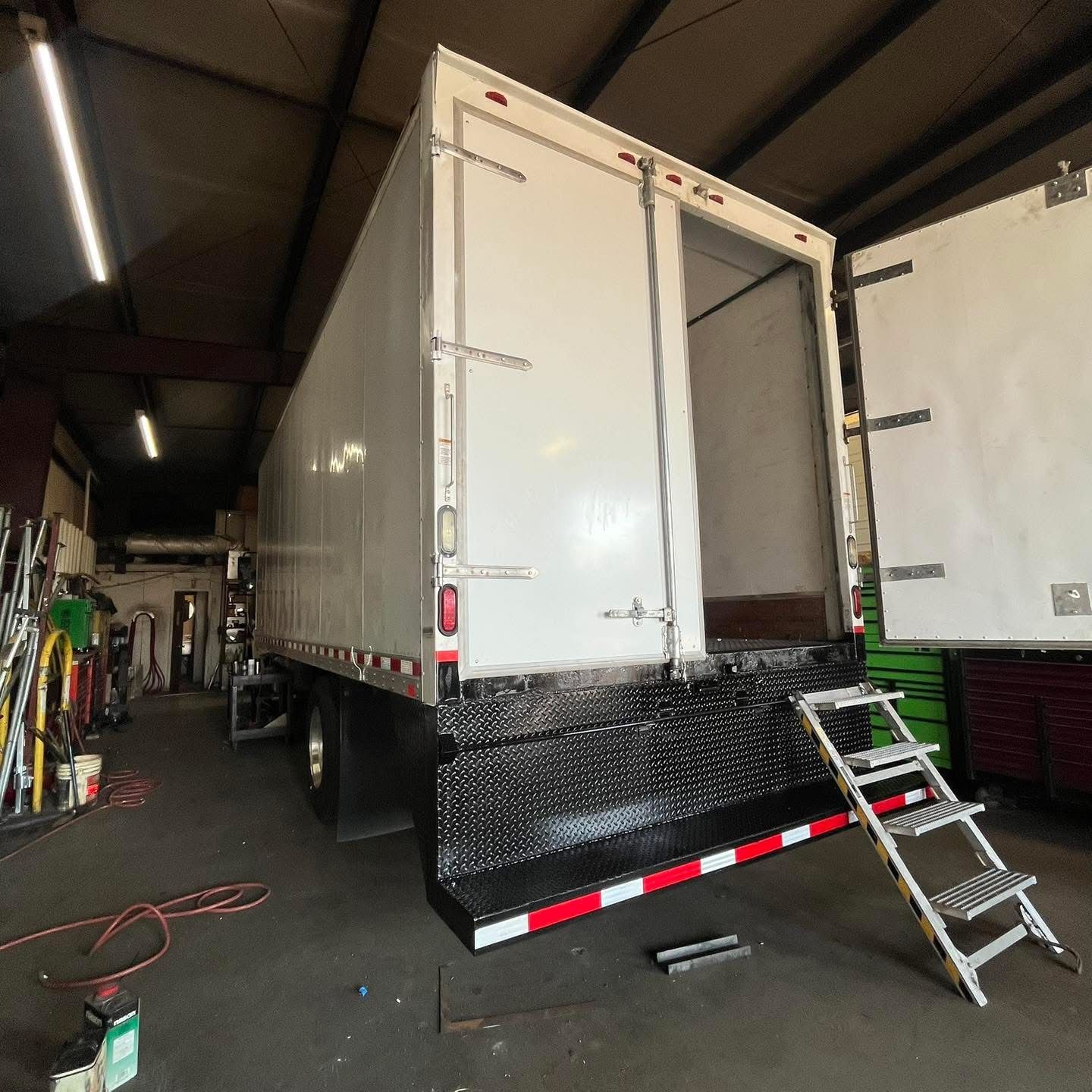 Mechanic working on the engine of a purple semi-truck outdoors.