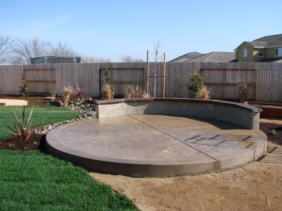 A round concrete patio with a wooden fence in the background