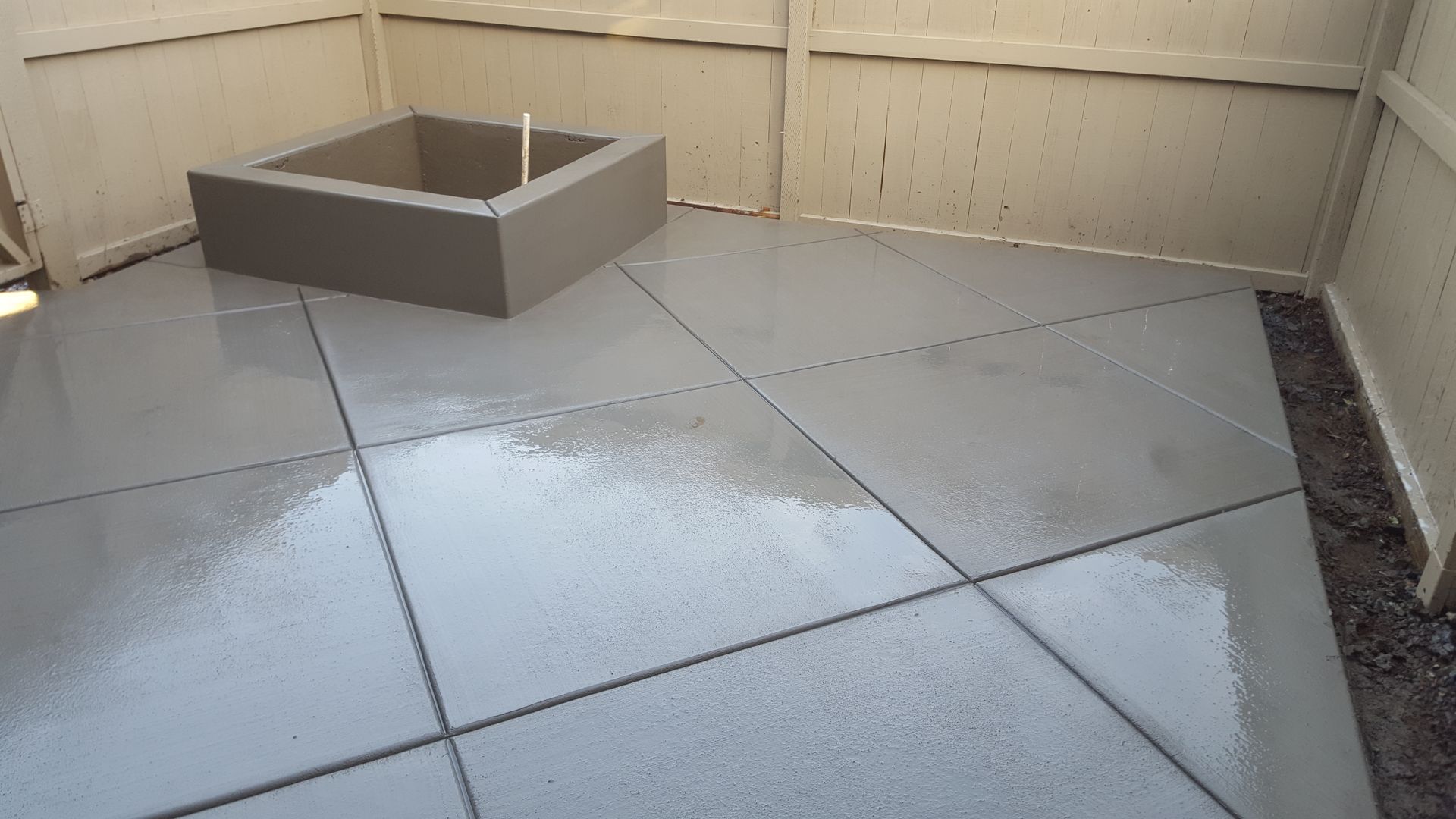 A concrete floor with a square planter in the middle of it.