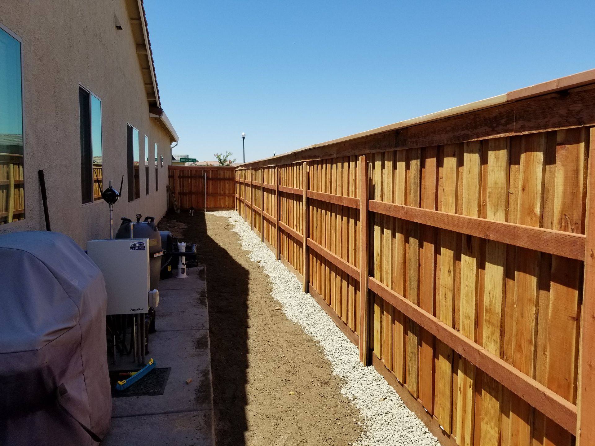 A wooden fence is along the side of a house.