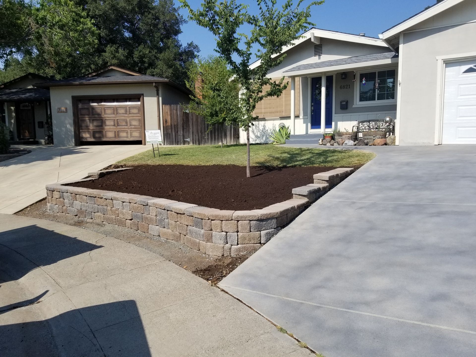 A house with a concrete driveway and a stone wall in front of it