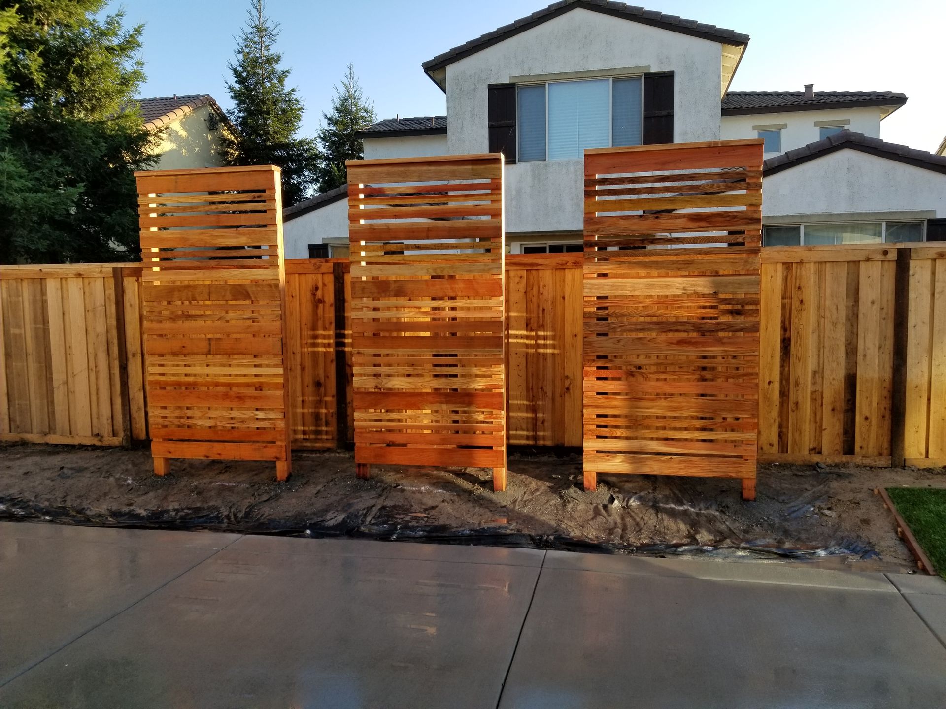 A wooden fence is in front of a house.