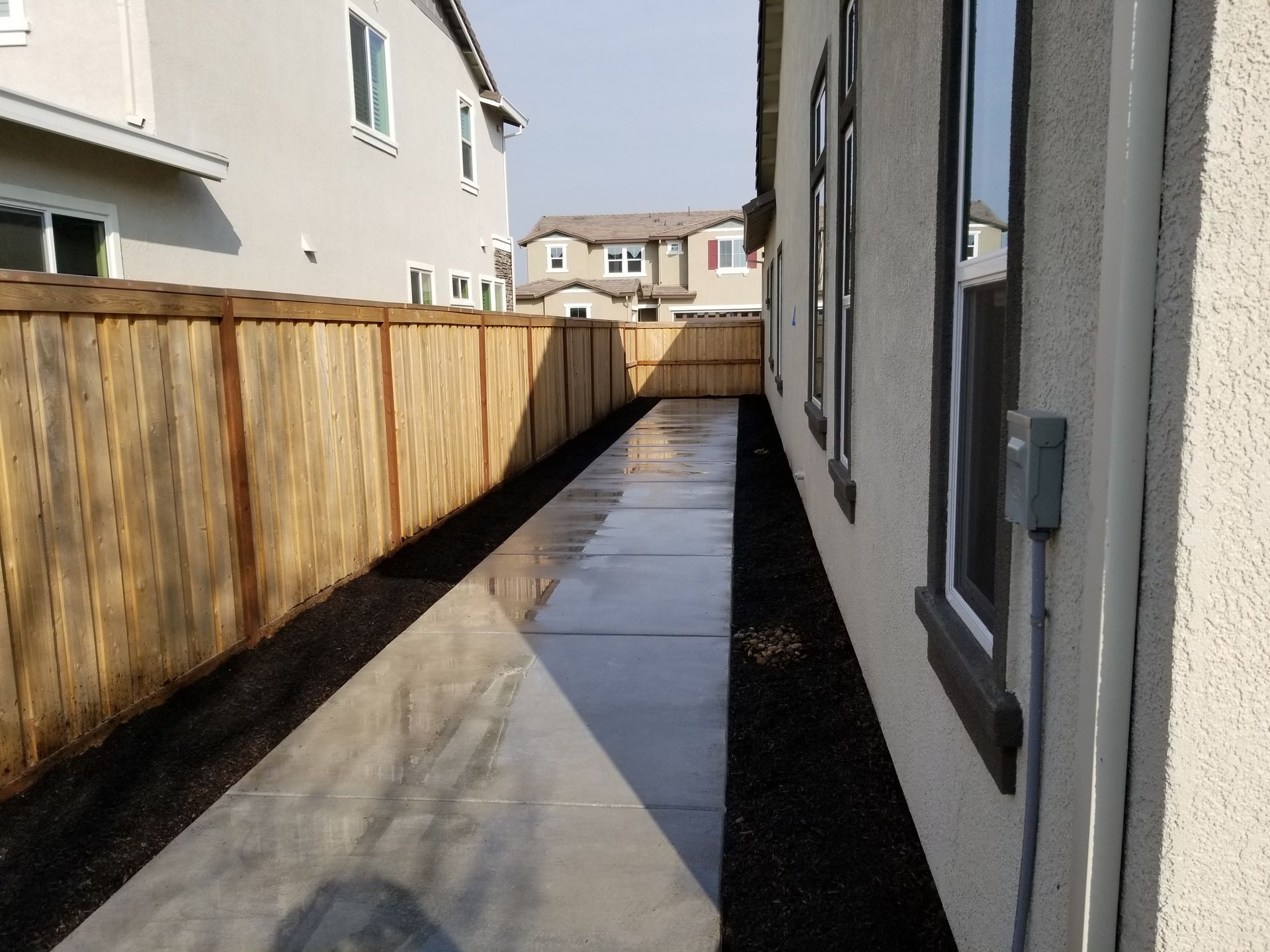 A sidewalk leading to a house with a wooden fence