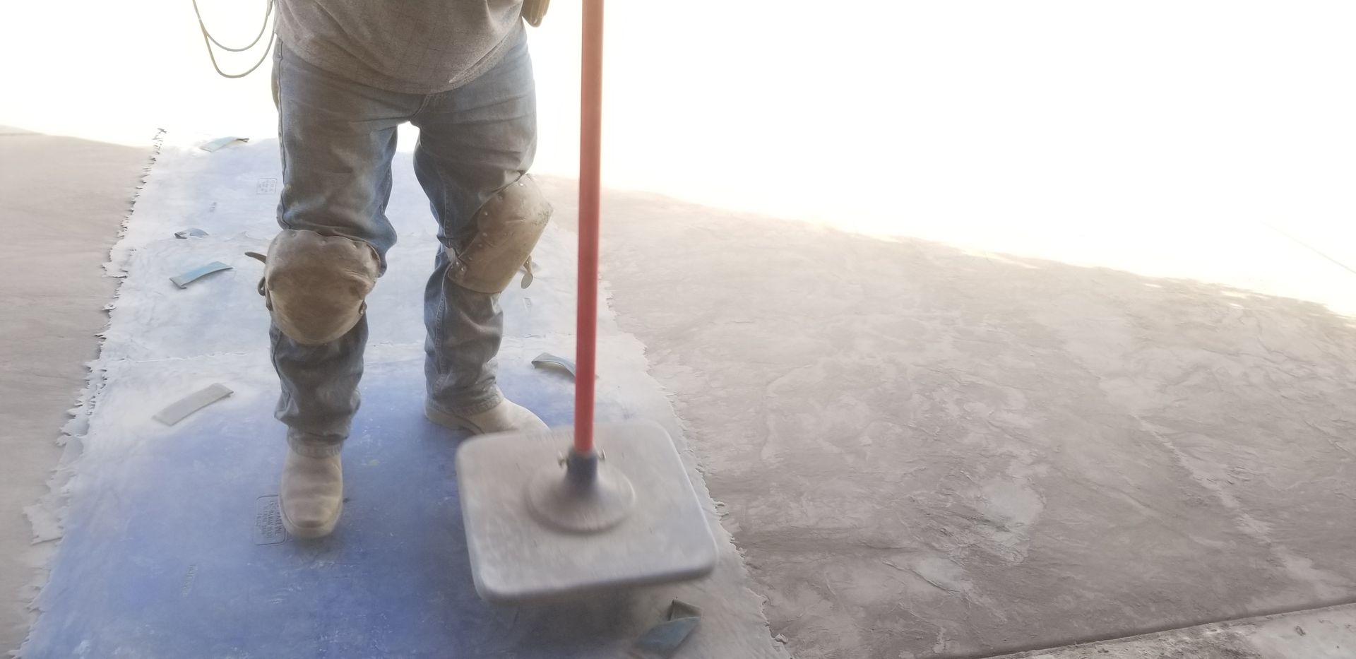 A man is standing on a concrete surface holding a mop.