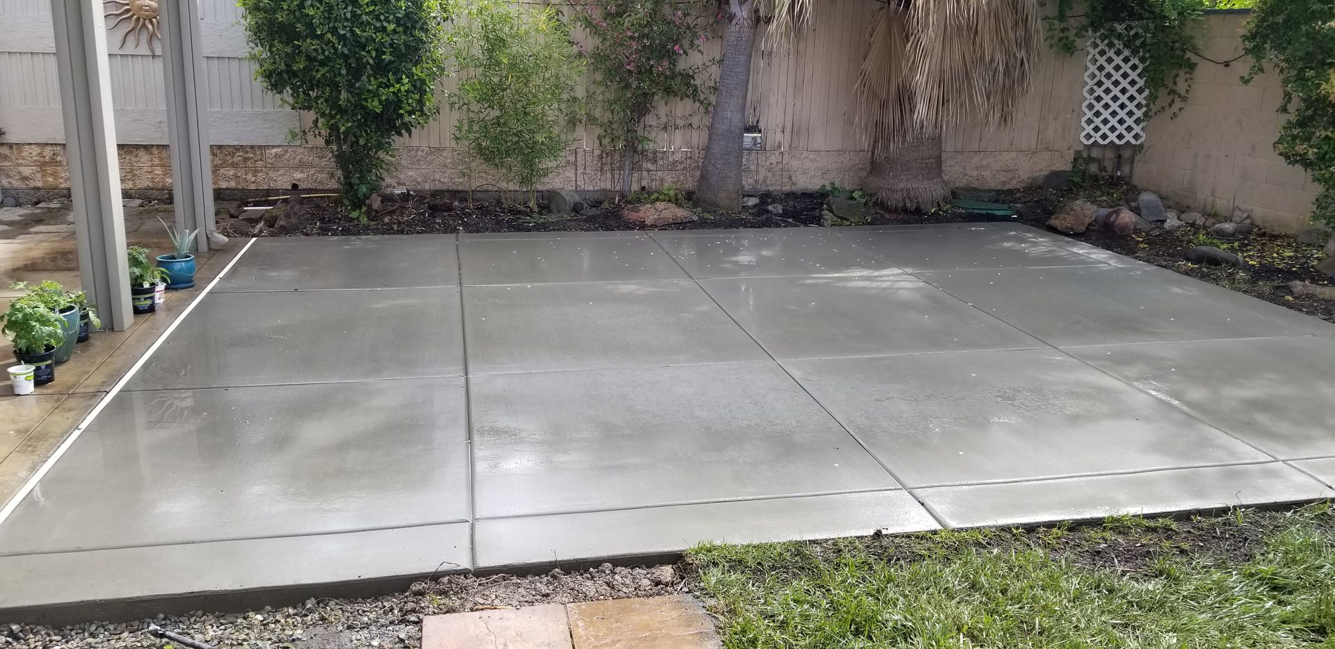 A concrete floor in a backyard with a fence in the background.
