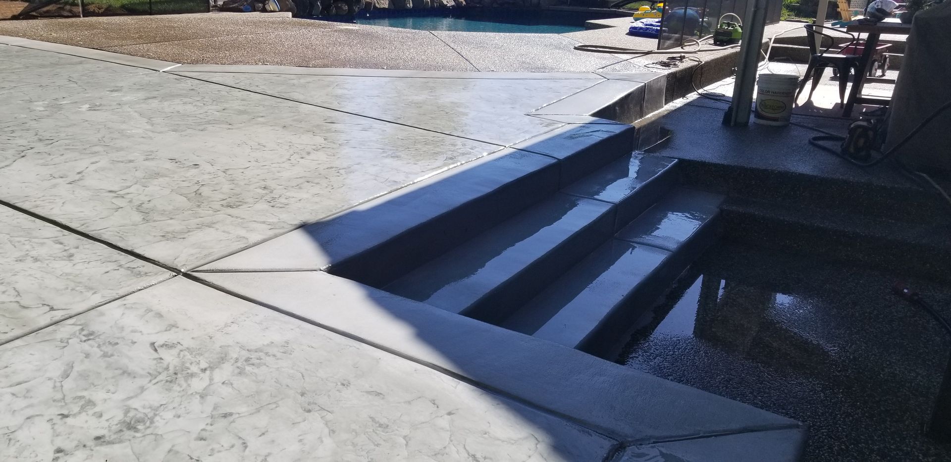 A concrete patio with stairs leading up to a pool.