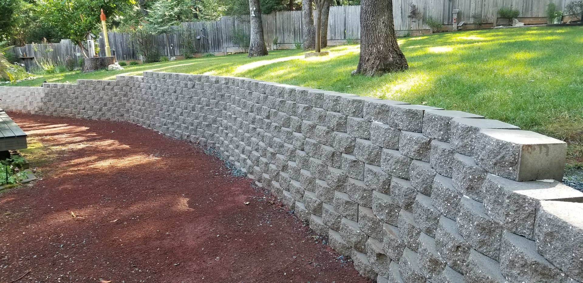 A stone wall is in the middle of a lush green yard.