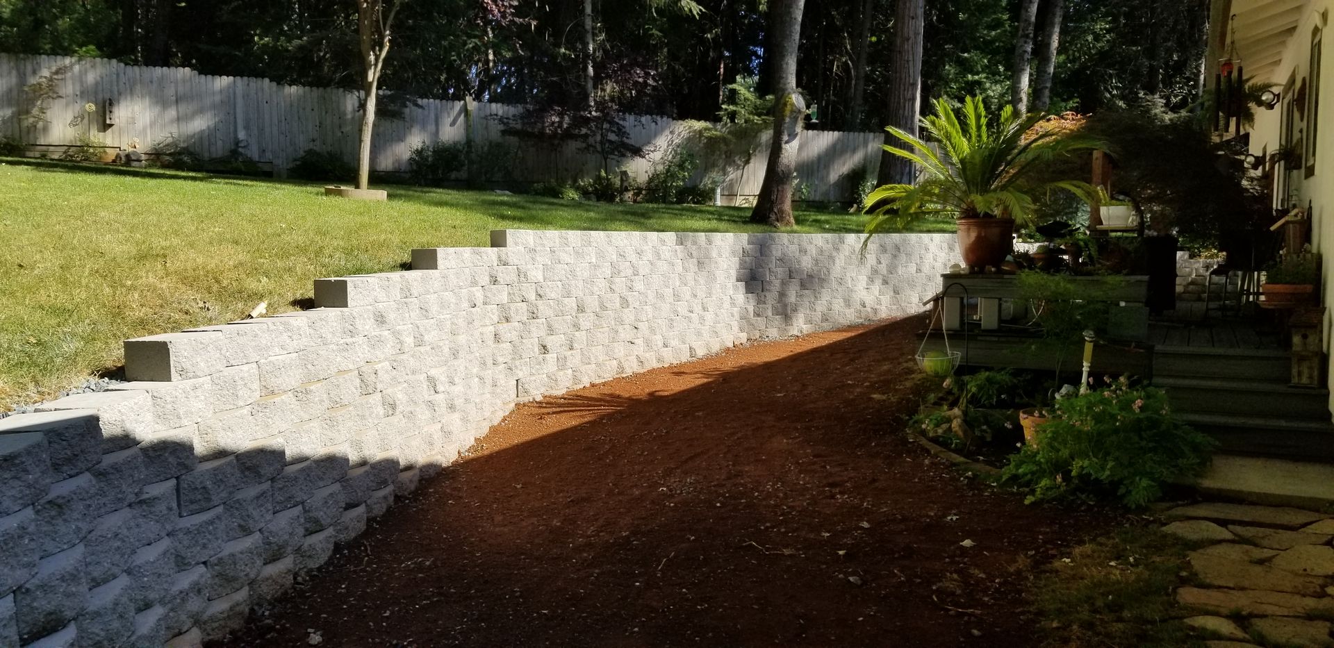 There is a stone wall in the backyard of a house.