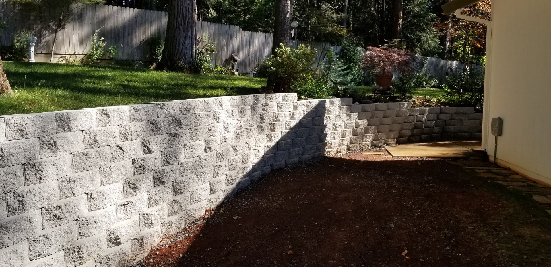 A brick wall in a backyard with a shadow on it