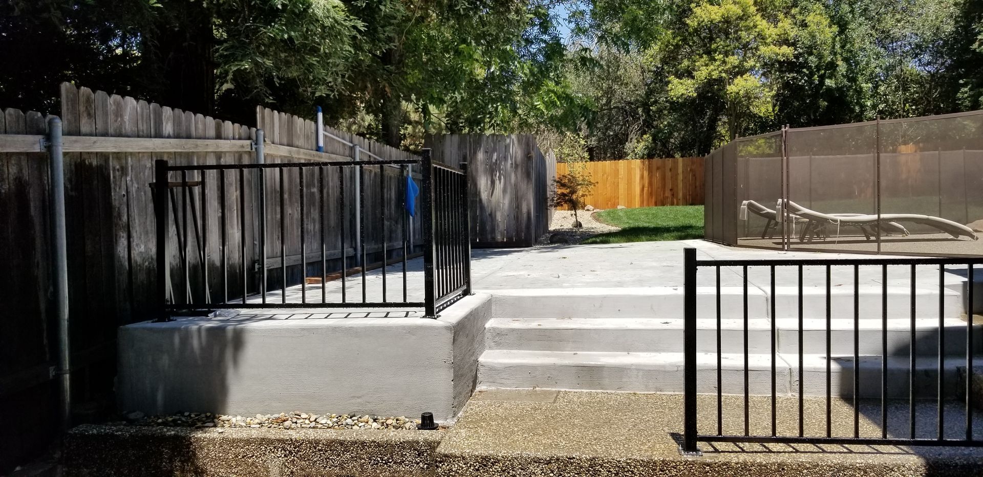 A fence surrounds a patio with a table and chairs.