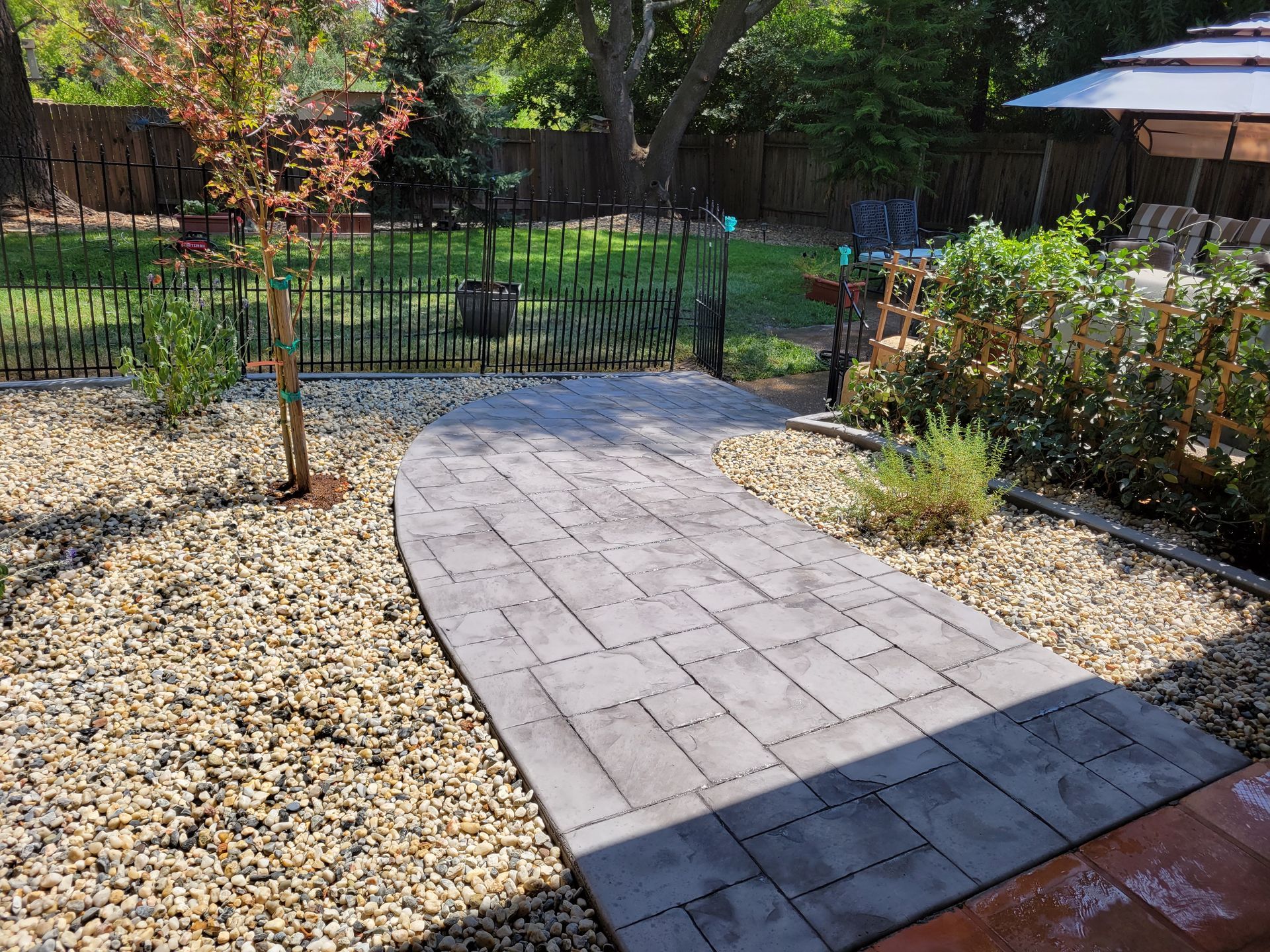 A stone walkway leading to a patio in a backyard.