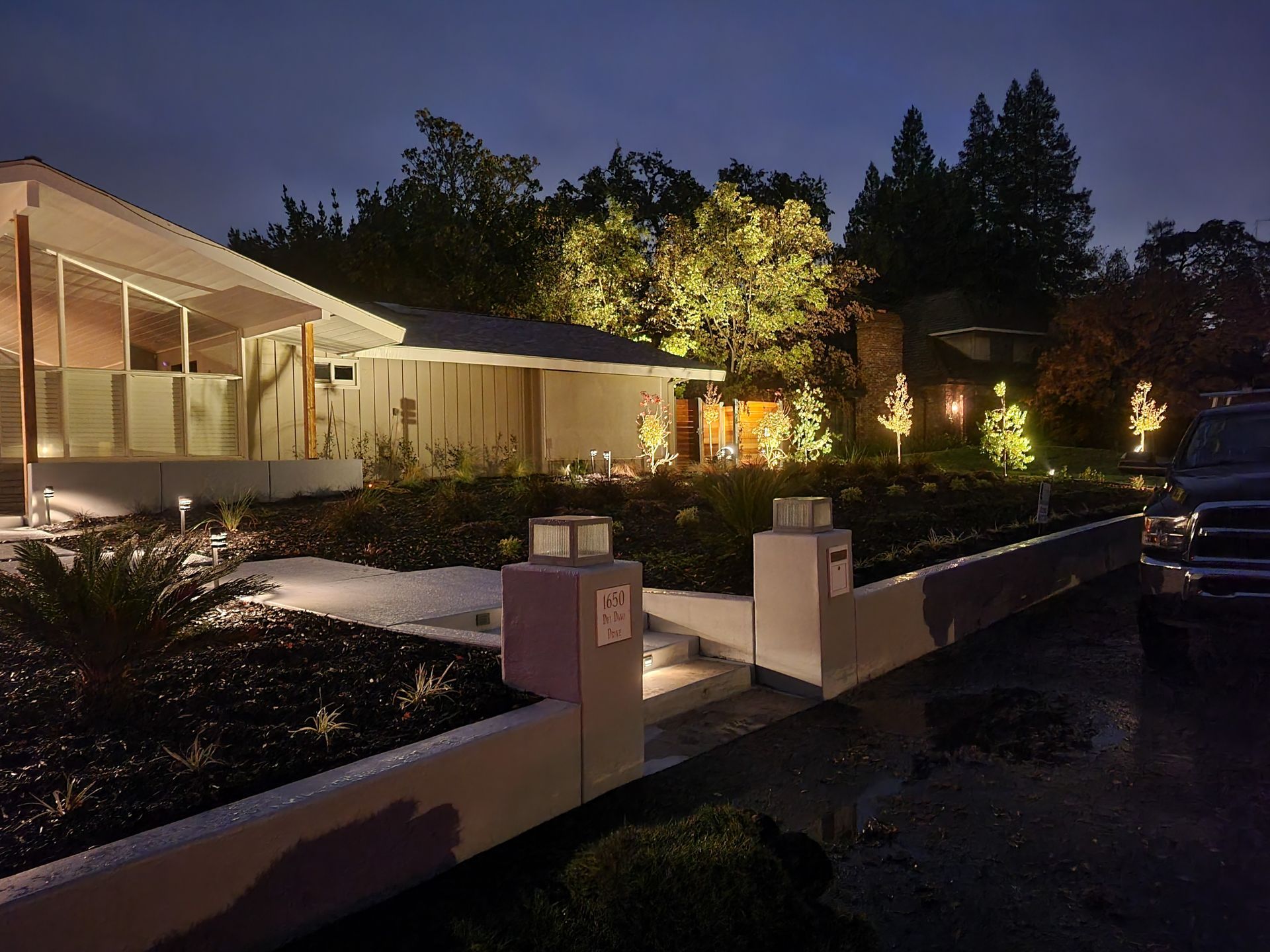 A house is lit up at night with a car parked in front of it