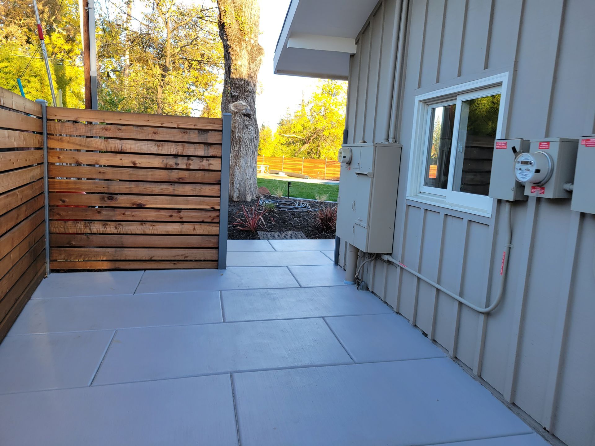 A patio with a wooden fence and a window on the side of a house.