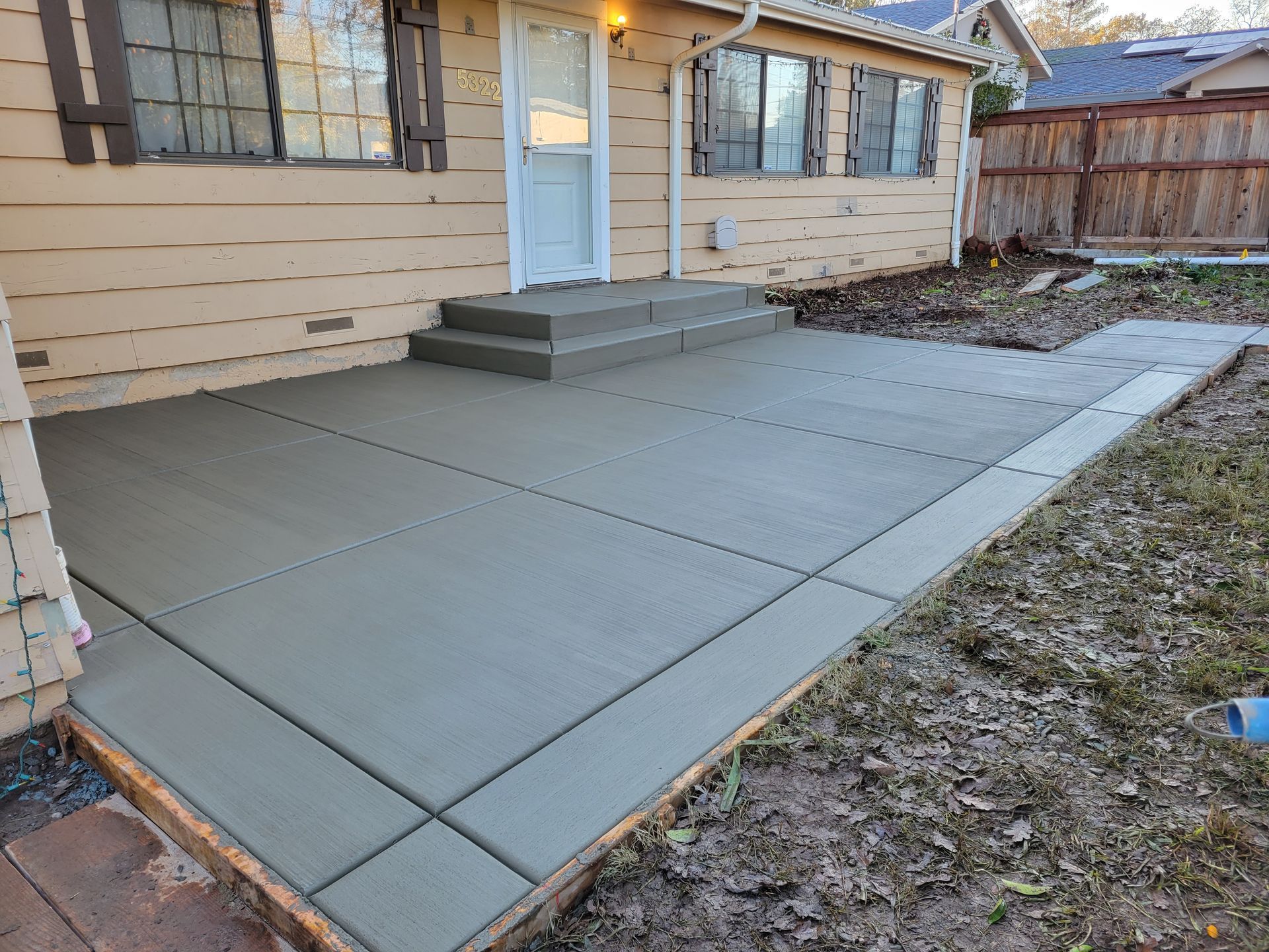 A concrete patio is being built in front of a house.