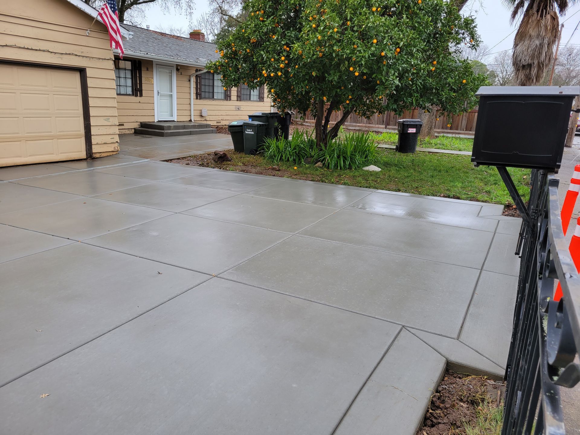 A concrete driveway with a mailbox in front of a house.