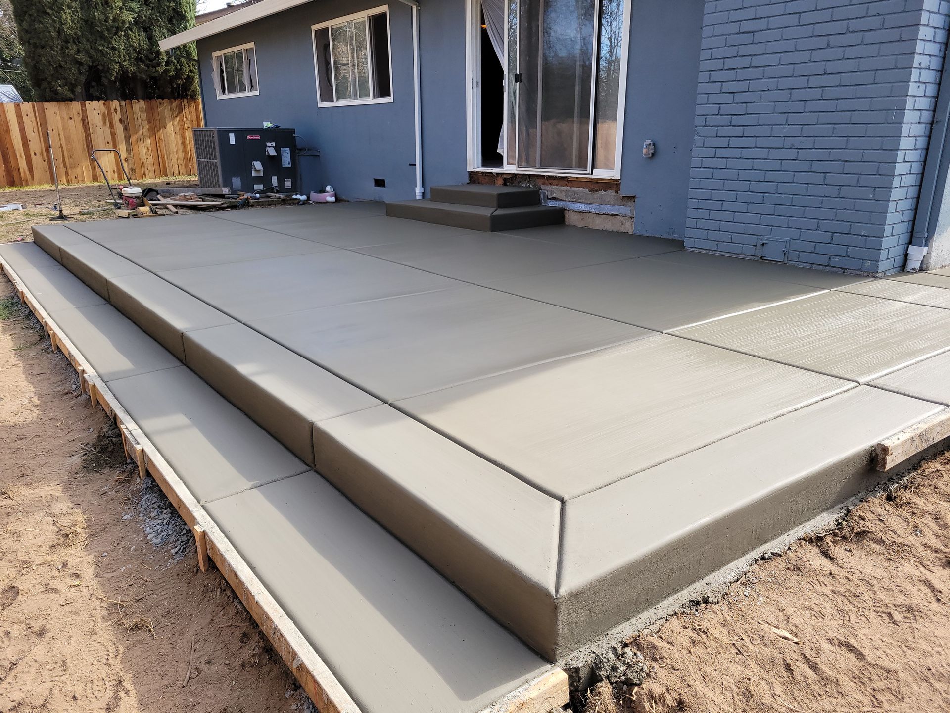 A concrete patio is being built in front of a house