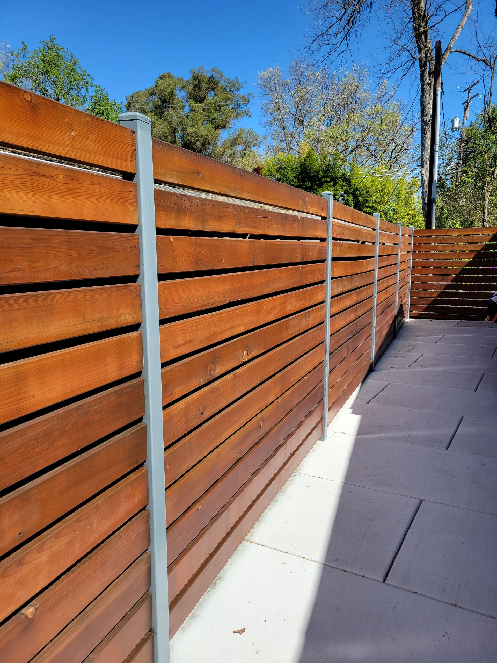 A wooden fence surrounds a patio with trees in the background.