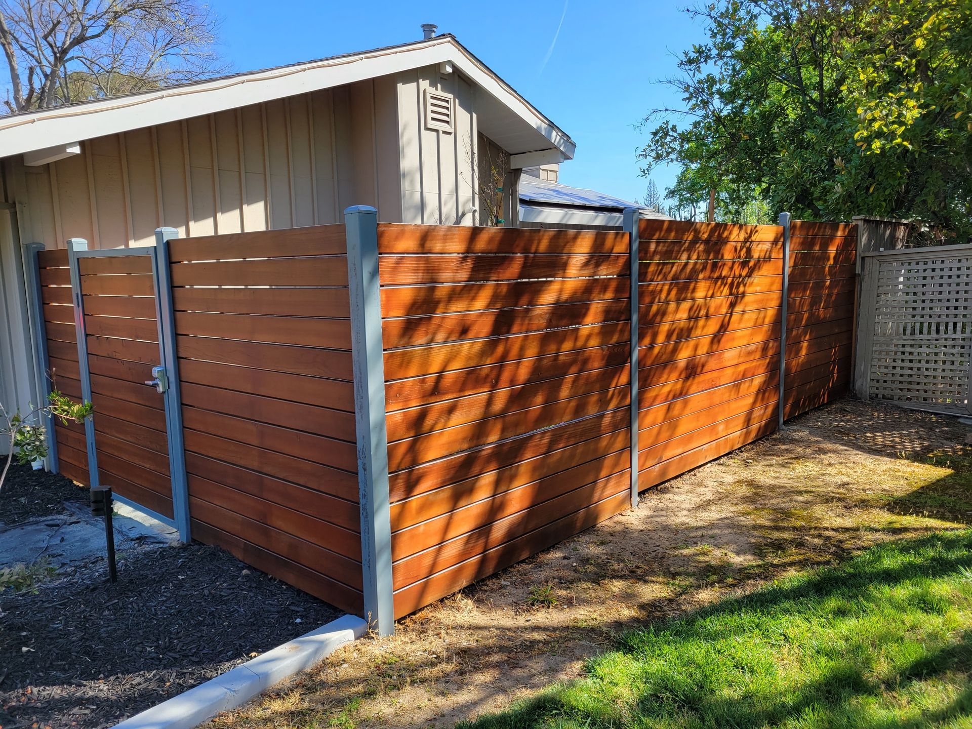 A wooden fence is in front of a house.