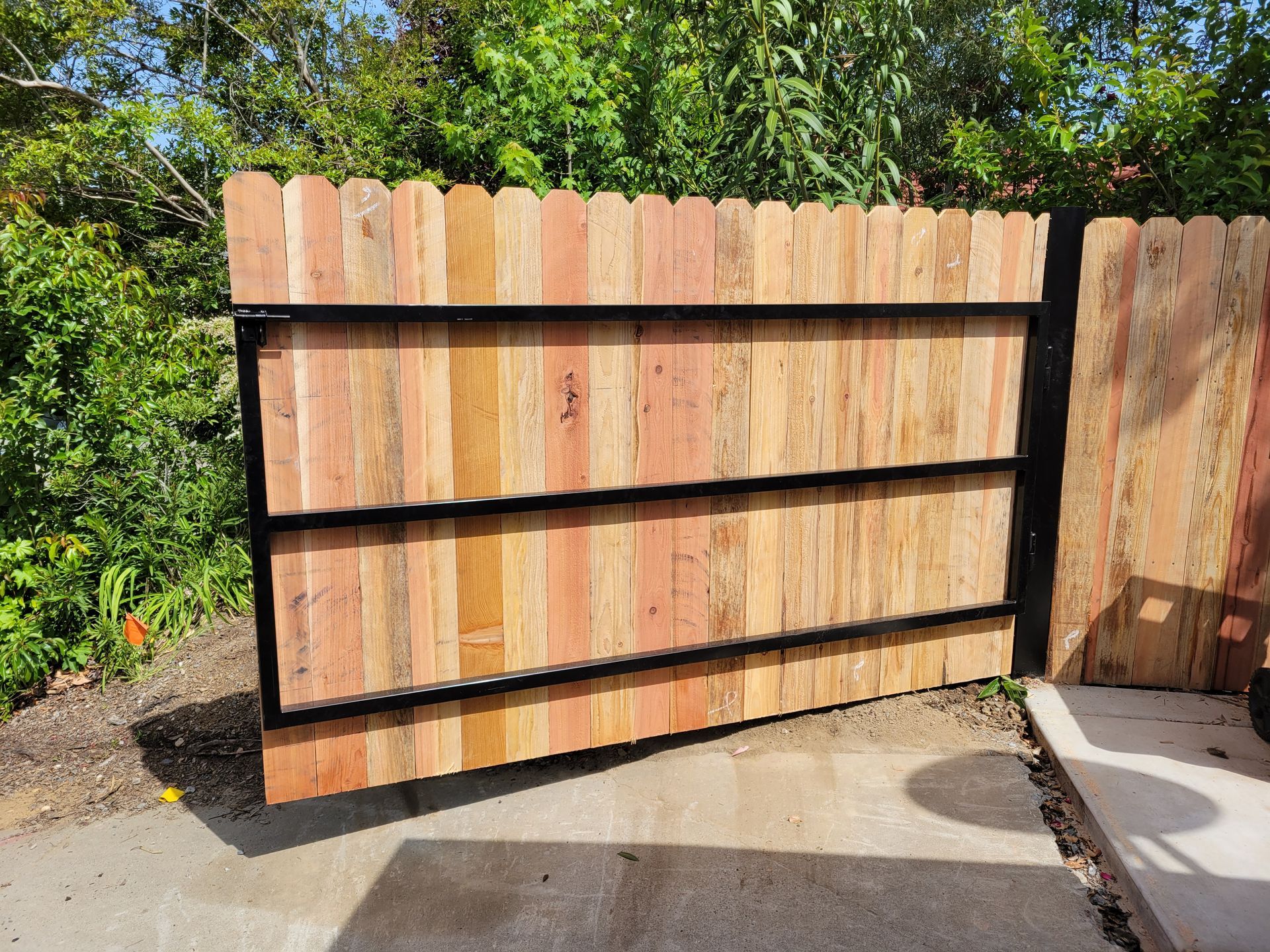 A wooden fence with a metal frame is sitting on the side of a road.