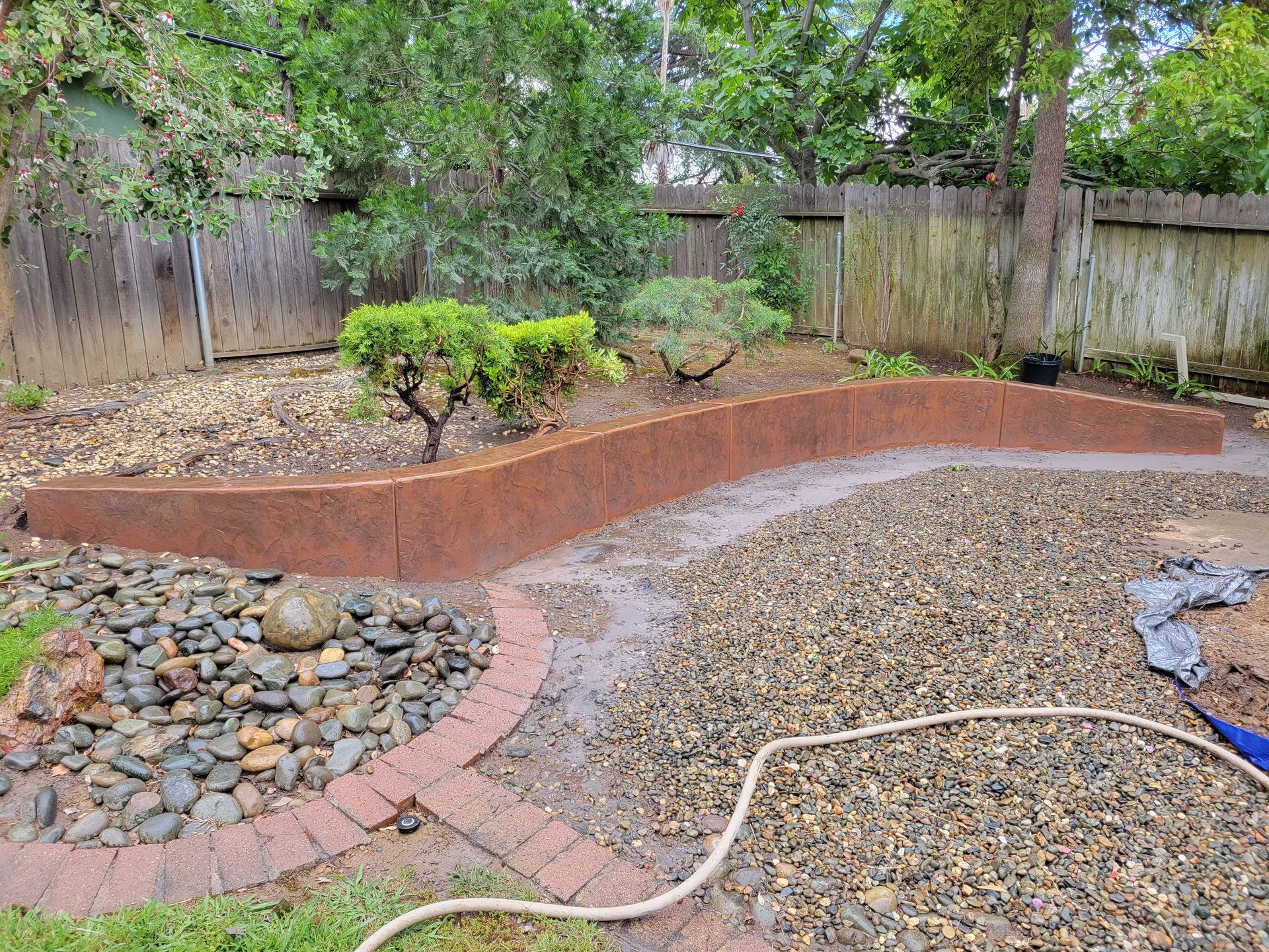 A hose is sitting in the middle of a backyard.