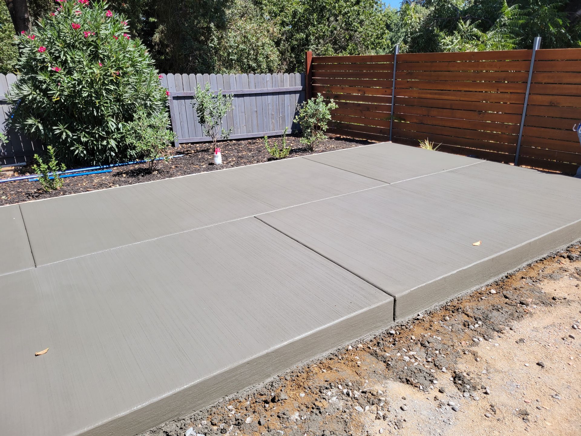 A concrete patio with a wooden fence in the background.