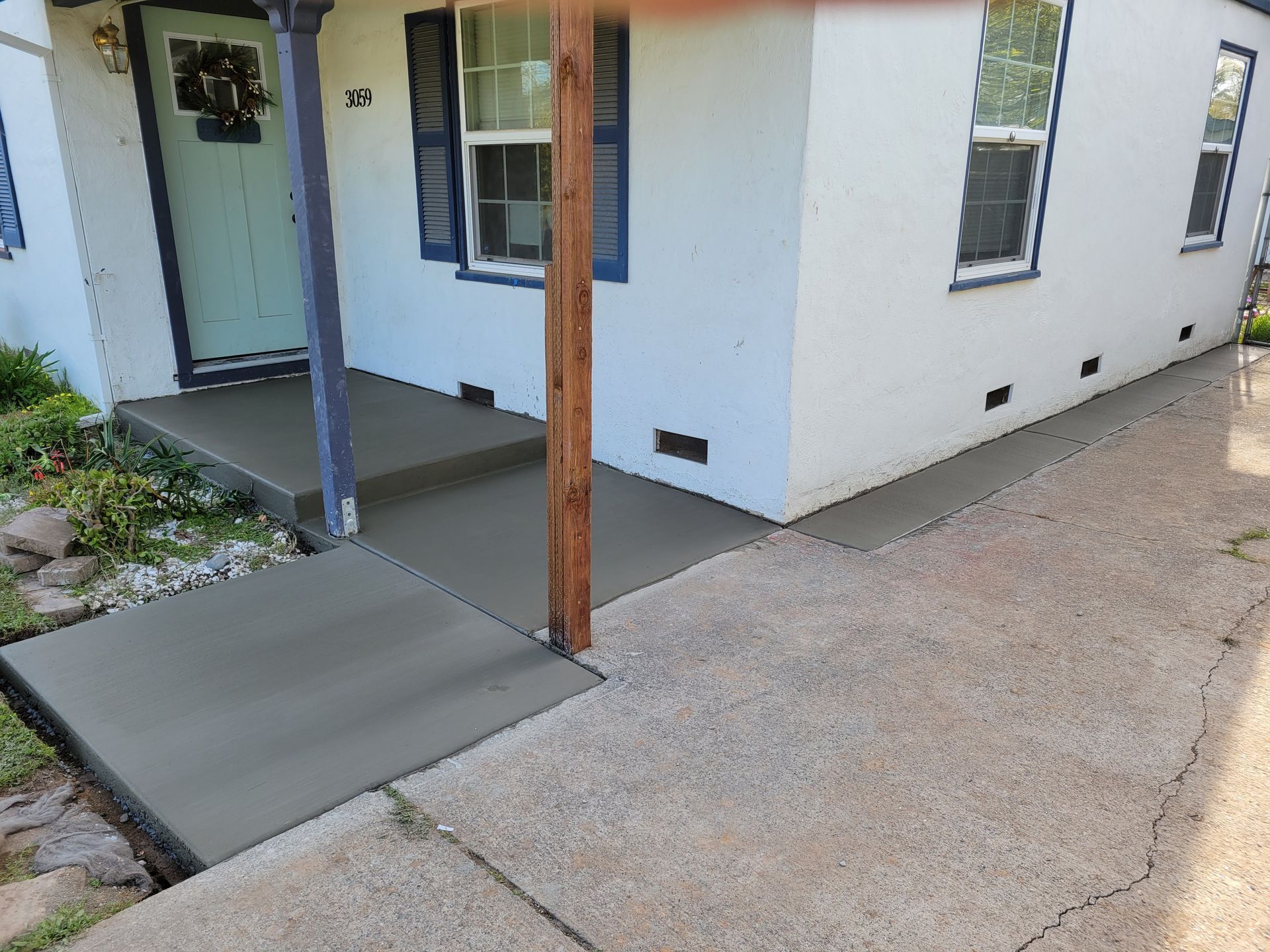 A white house with a concrete walkway leading to the front door.