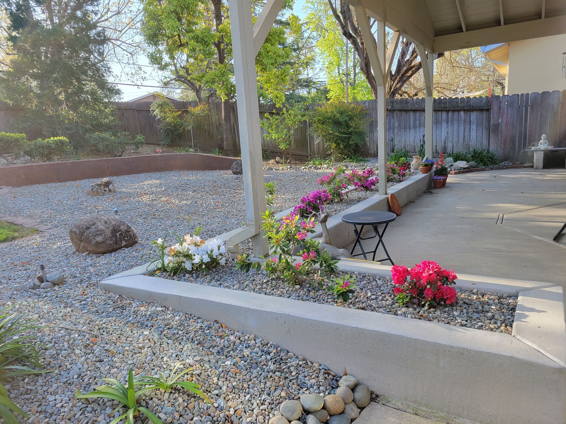 A garden with flowers and rocks in front of a house.