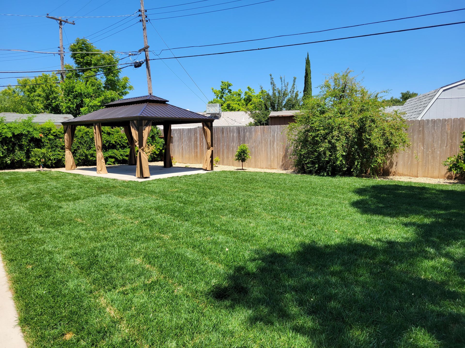 There is a gazebo in the middle of a lush green yard.