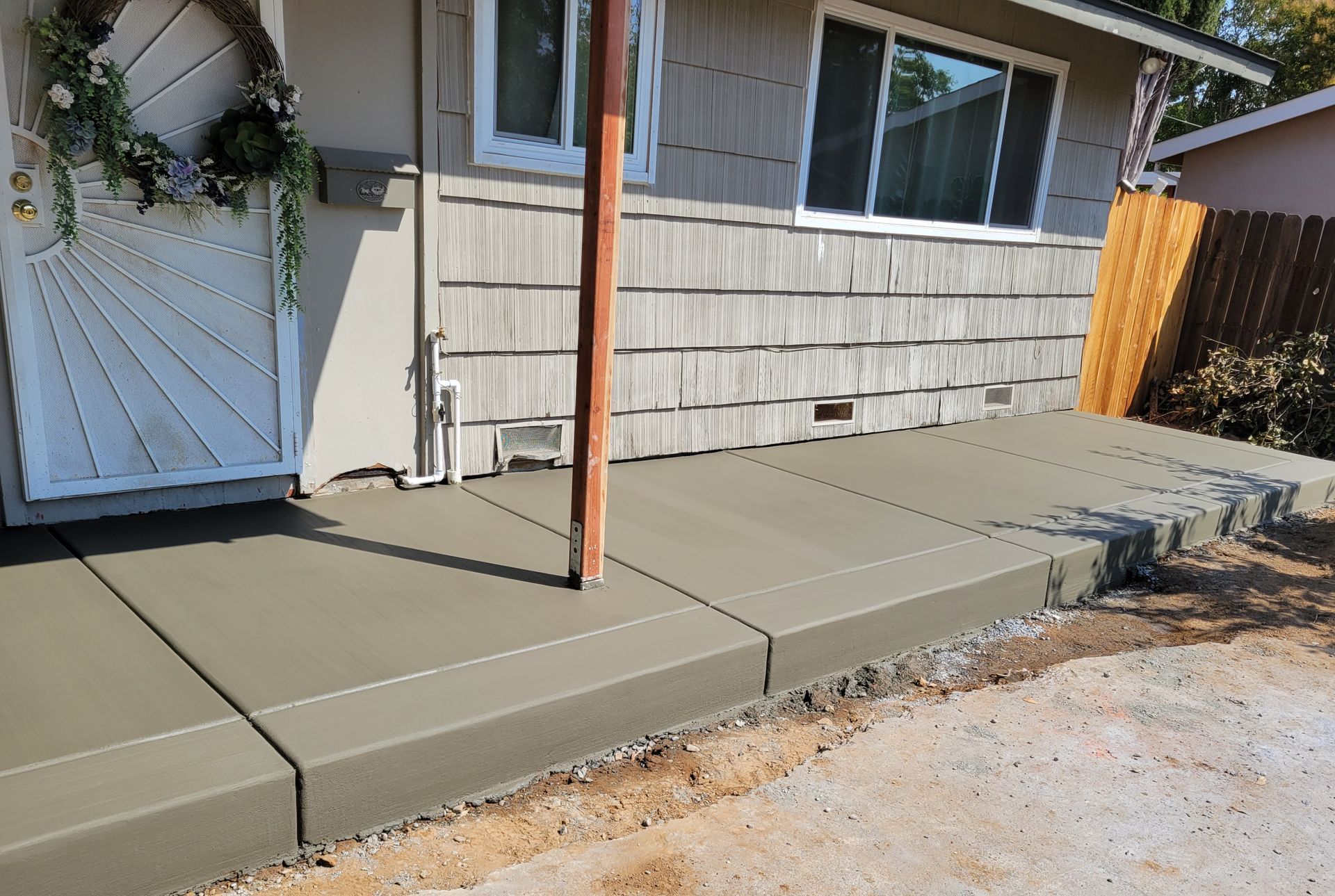 A concrete walkway is being built in front of a house.