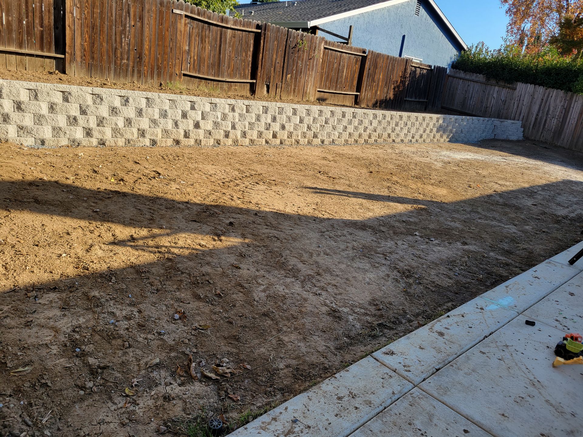 A backyard with a brick wall and a wooden fence.