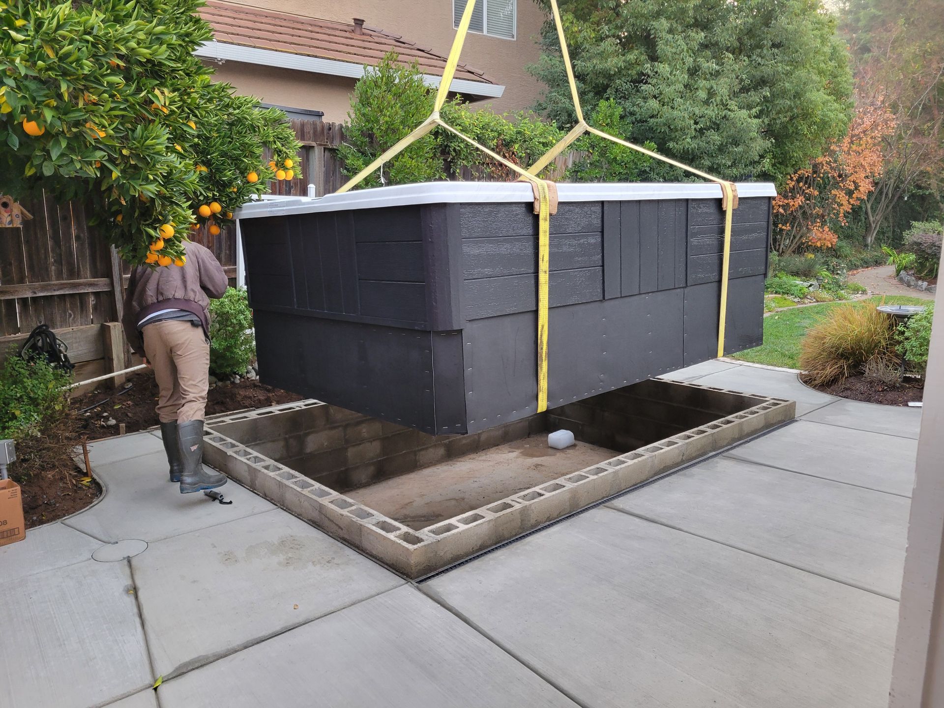 A man is lifting a hot tub into a hole in the ground.