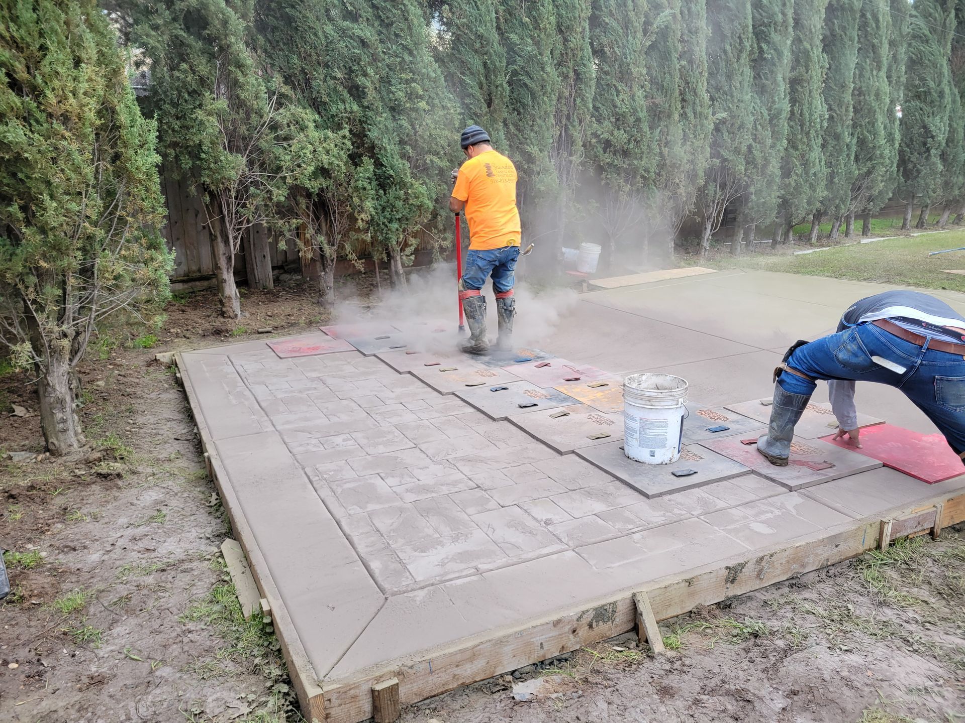 Two men are working on a concrete driveway.