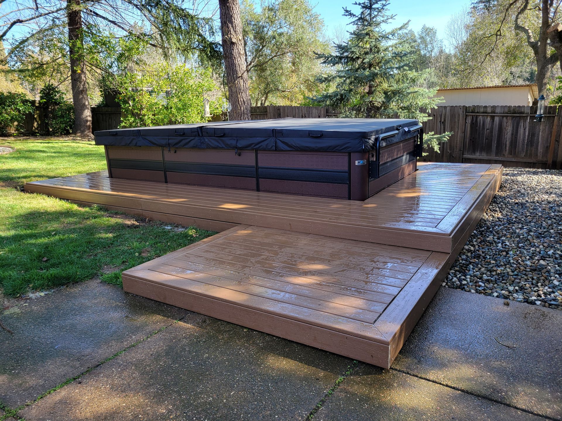 A hot tub is sitting on top of a wooden deck in a backyard.