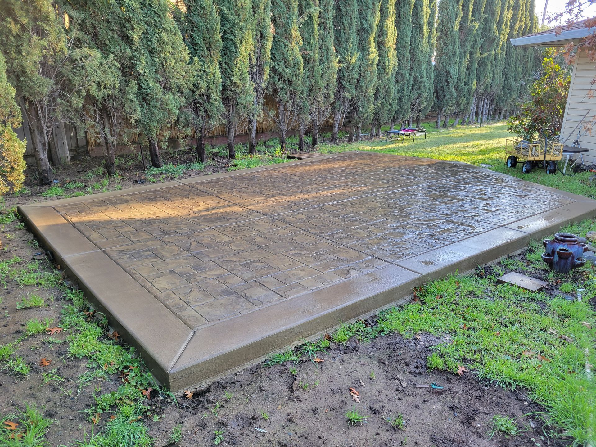 A concrete floor in a backyard with trees in the background.