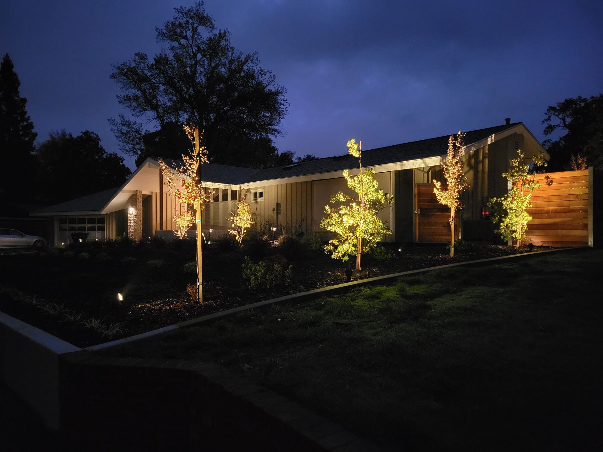 A house is lit up at night with trees in front of it