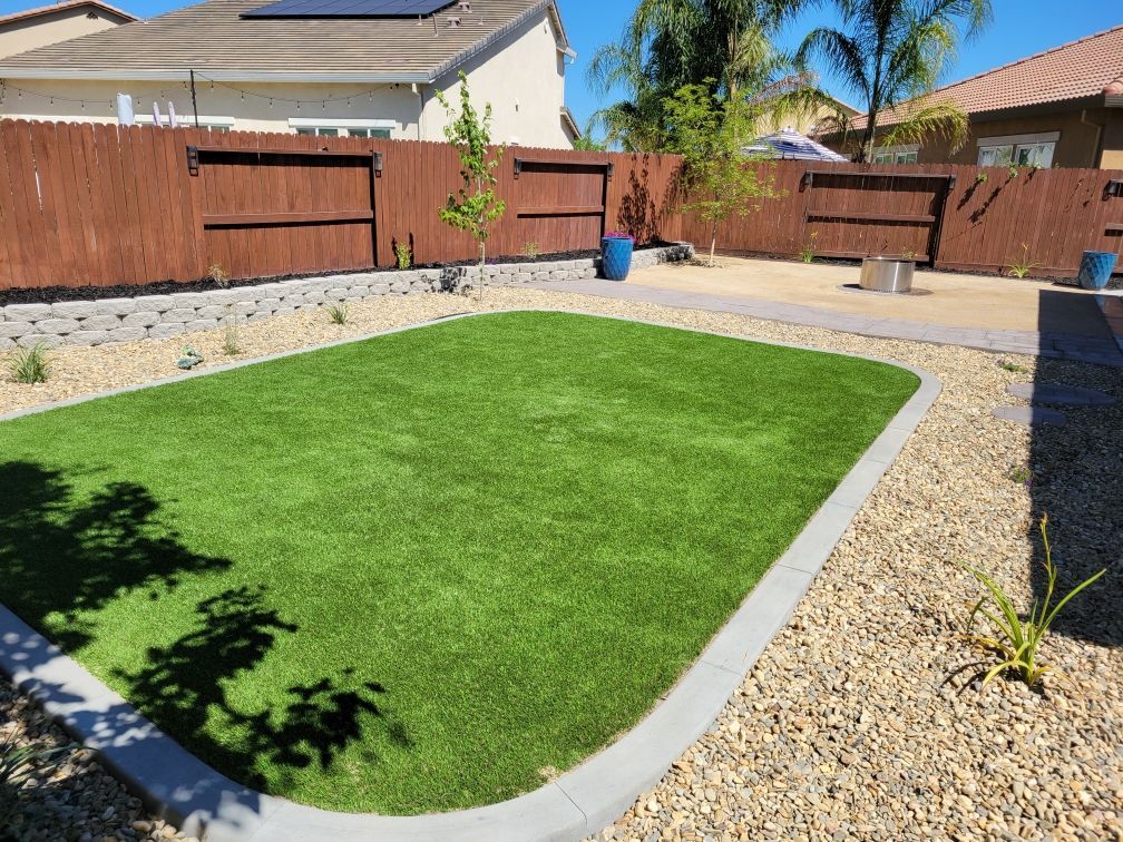 A backyard with a lush green lawn and a wooden fence.