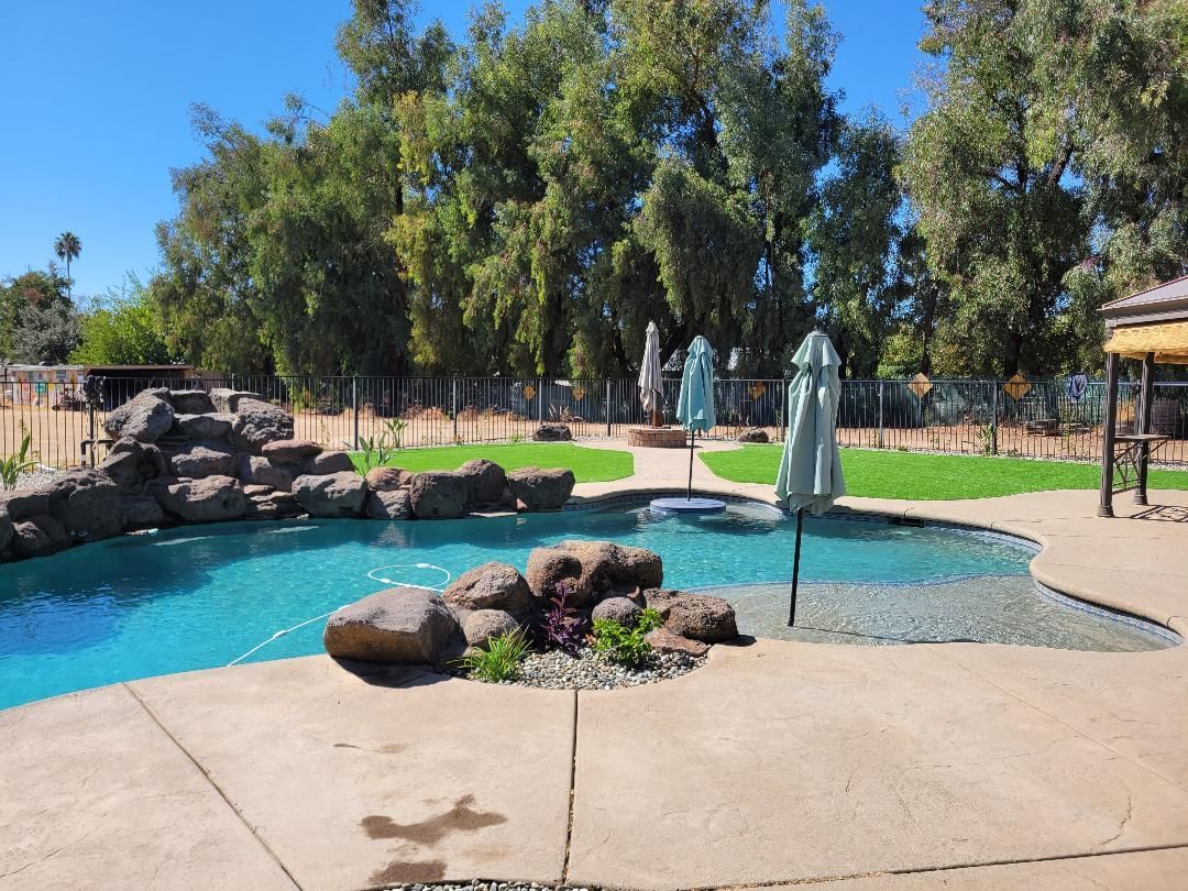 A large swimming pool surrounded by rocks and trees on a sunny day.