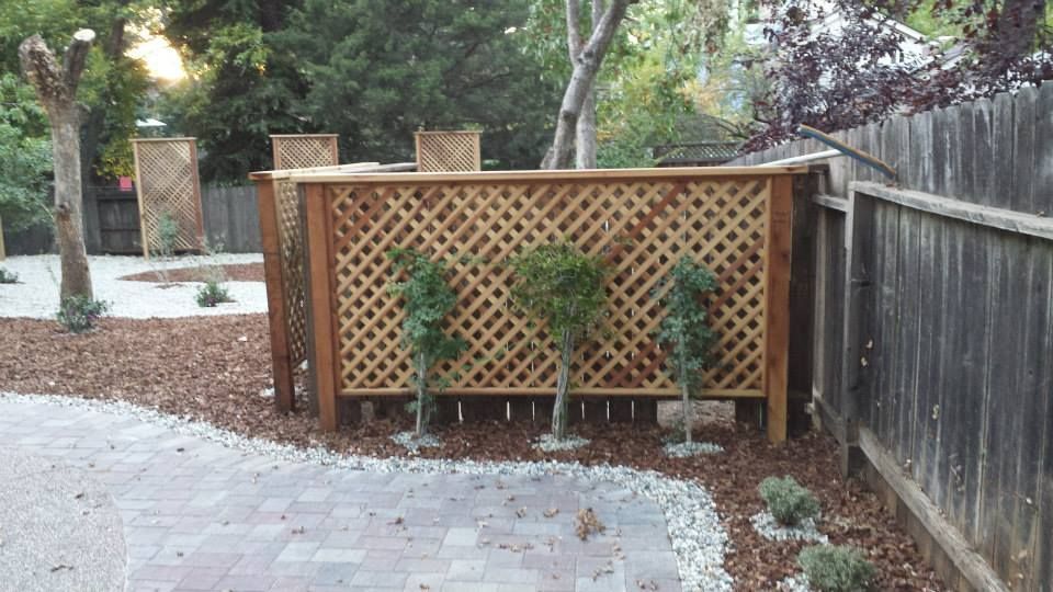A wooden lattice fence with trees in front of it