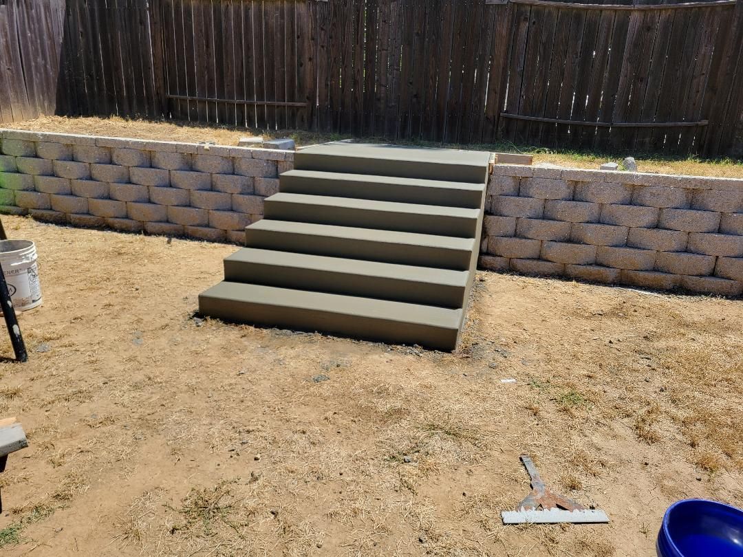 A set of concrete stairs are being built in a backyard.