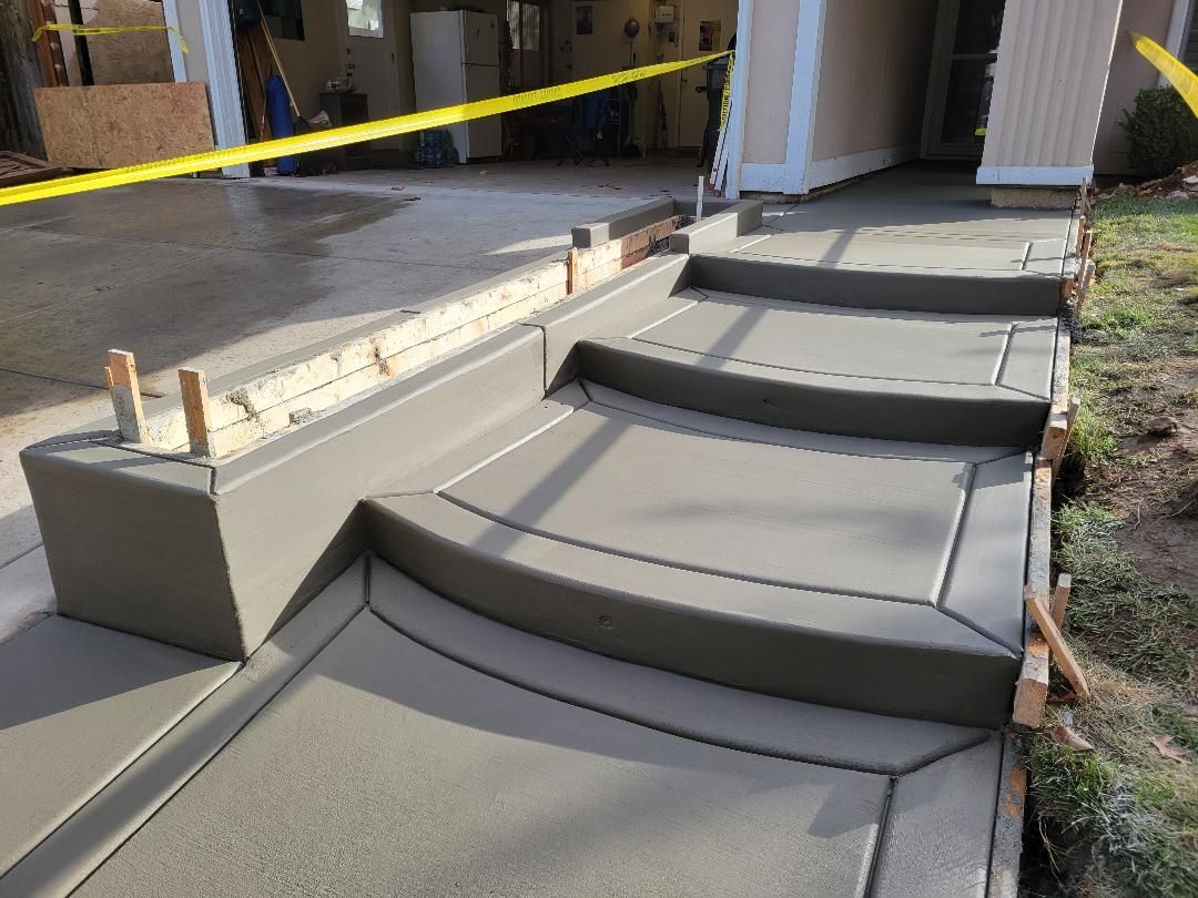 A concrete walkway is being built in front of a house.