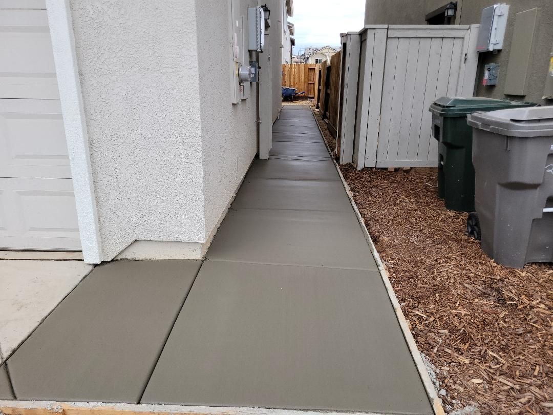 A concrete walkway between two buildings next to a trash can.