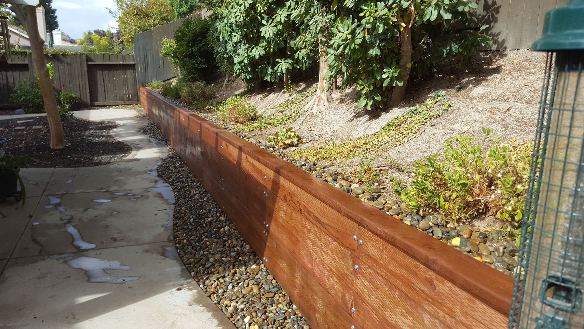 A wooden fence with a bird feeder in the background