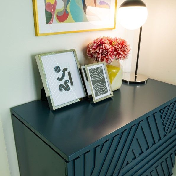 A blue dresser with three framed pictures on it