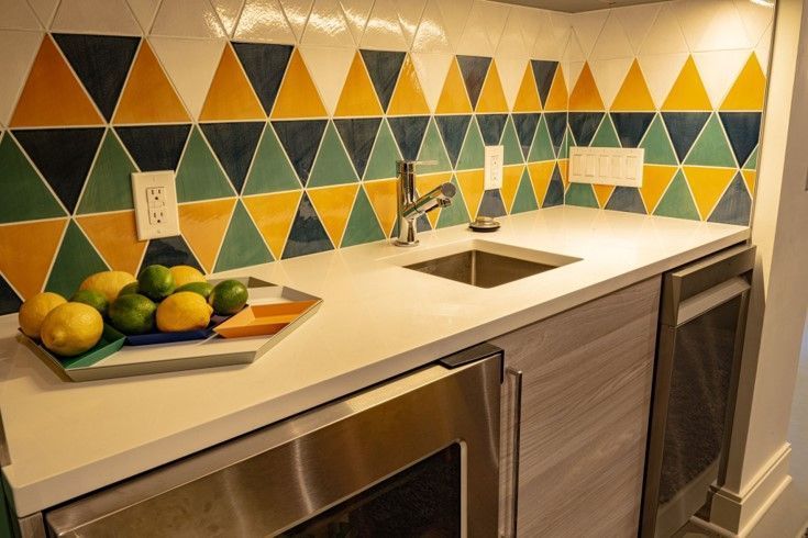 A kitchen with a sink and a tray of lemons and limes on the counter.