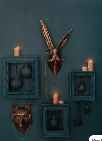 A rabbit head is hanging on a wall surrounded by frames and candles