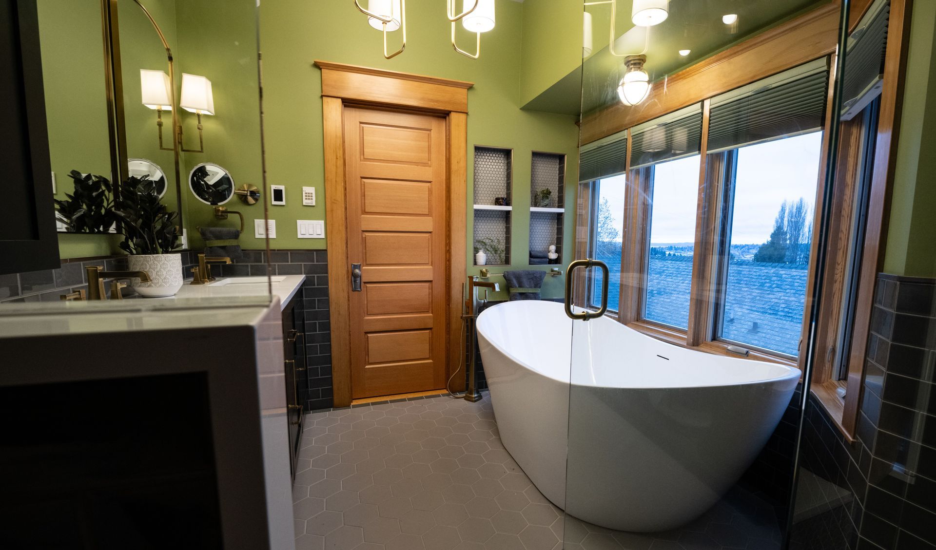 A bathroom with a tub , sink , mirror and window.