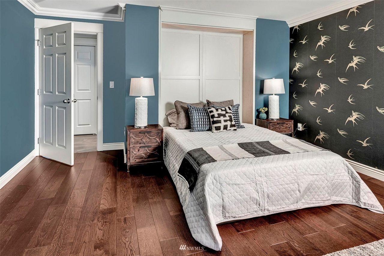 A bedroom with a bed , nightstands , lamps and blue walls.