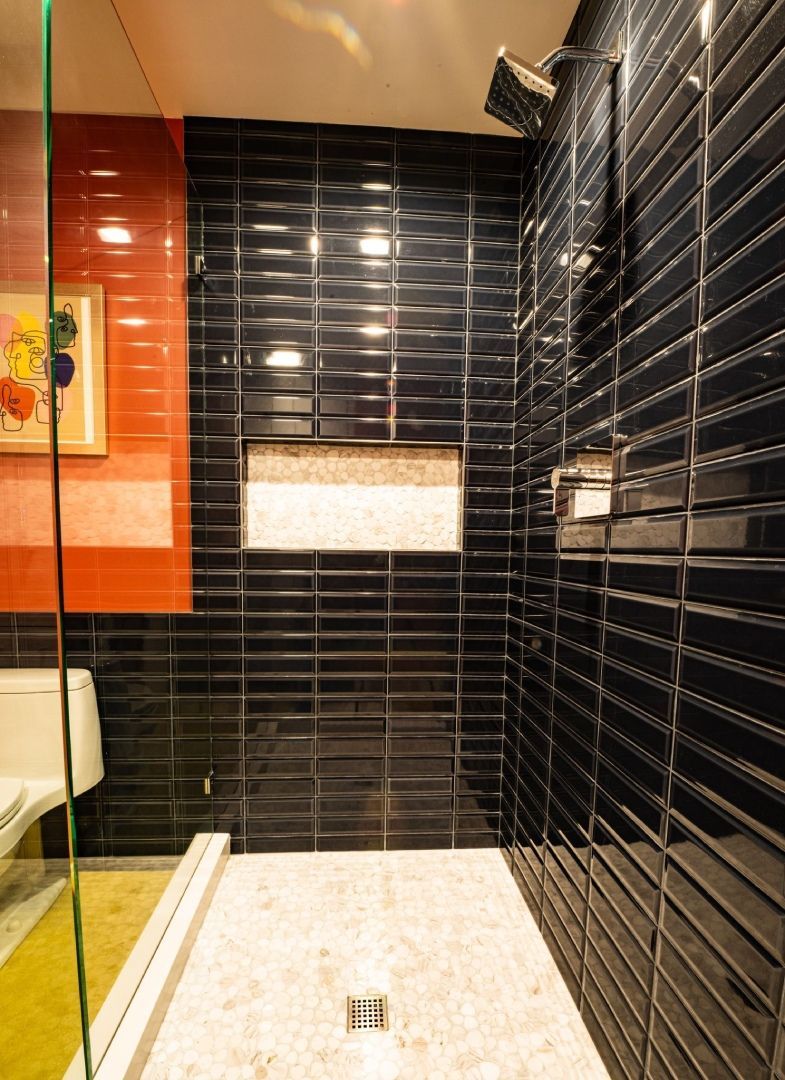 A bathroom with black tiles and a walk in shower